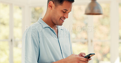 Phone, social media or text message with a man in his home, laughing at a meme while standing in the living room. Smile, comic or funny with a young male person typing on his mobile for communication