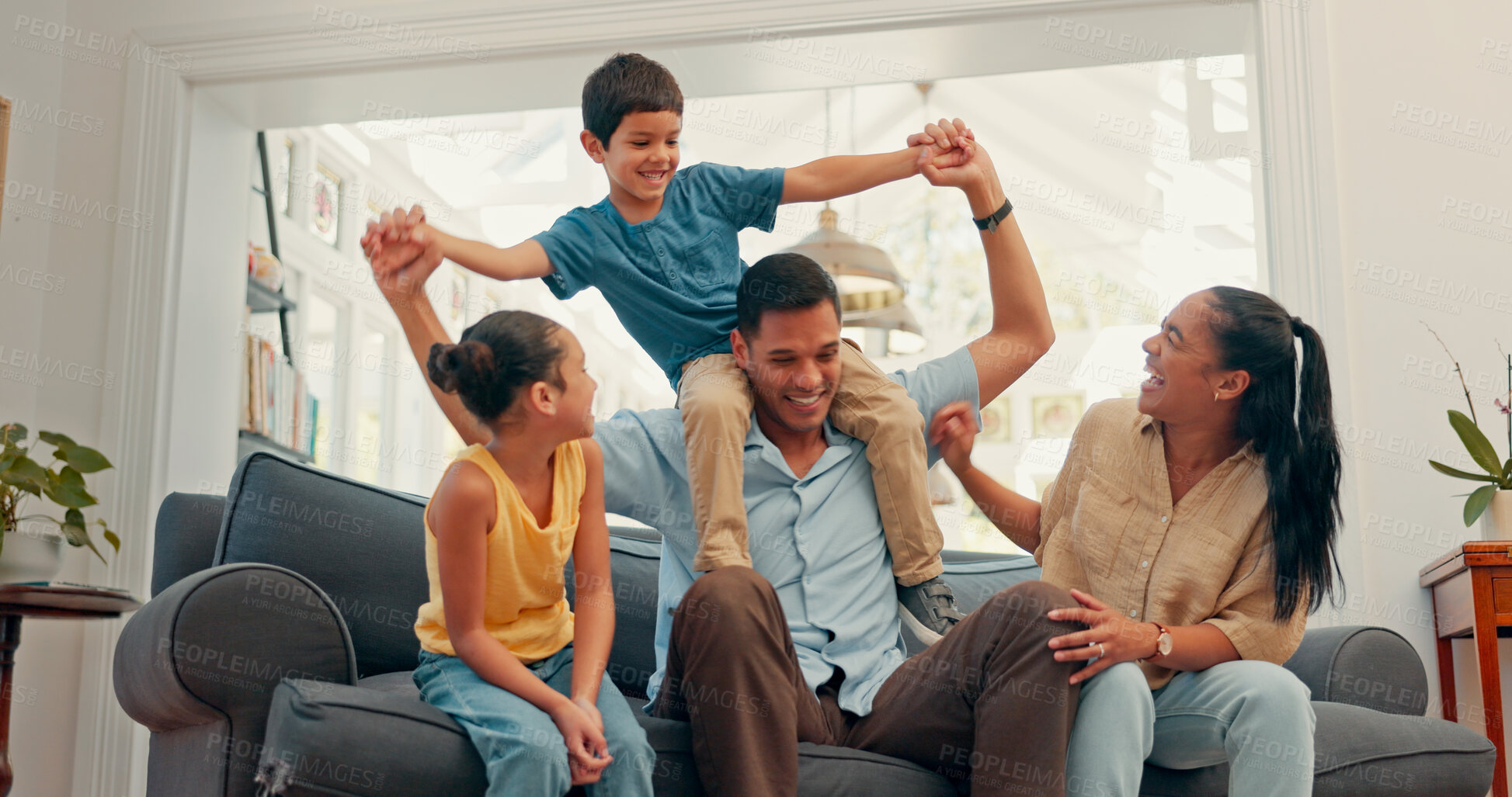 Buy stock photo Happy family, love and airplane fun on a sofa with care, security and support while bonding at home. Flying, balance and excited kids with parents in a living room for playing shoulder games together