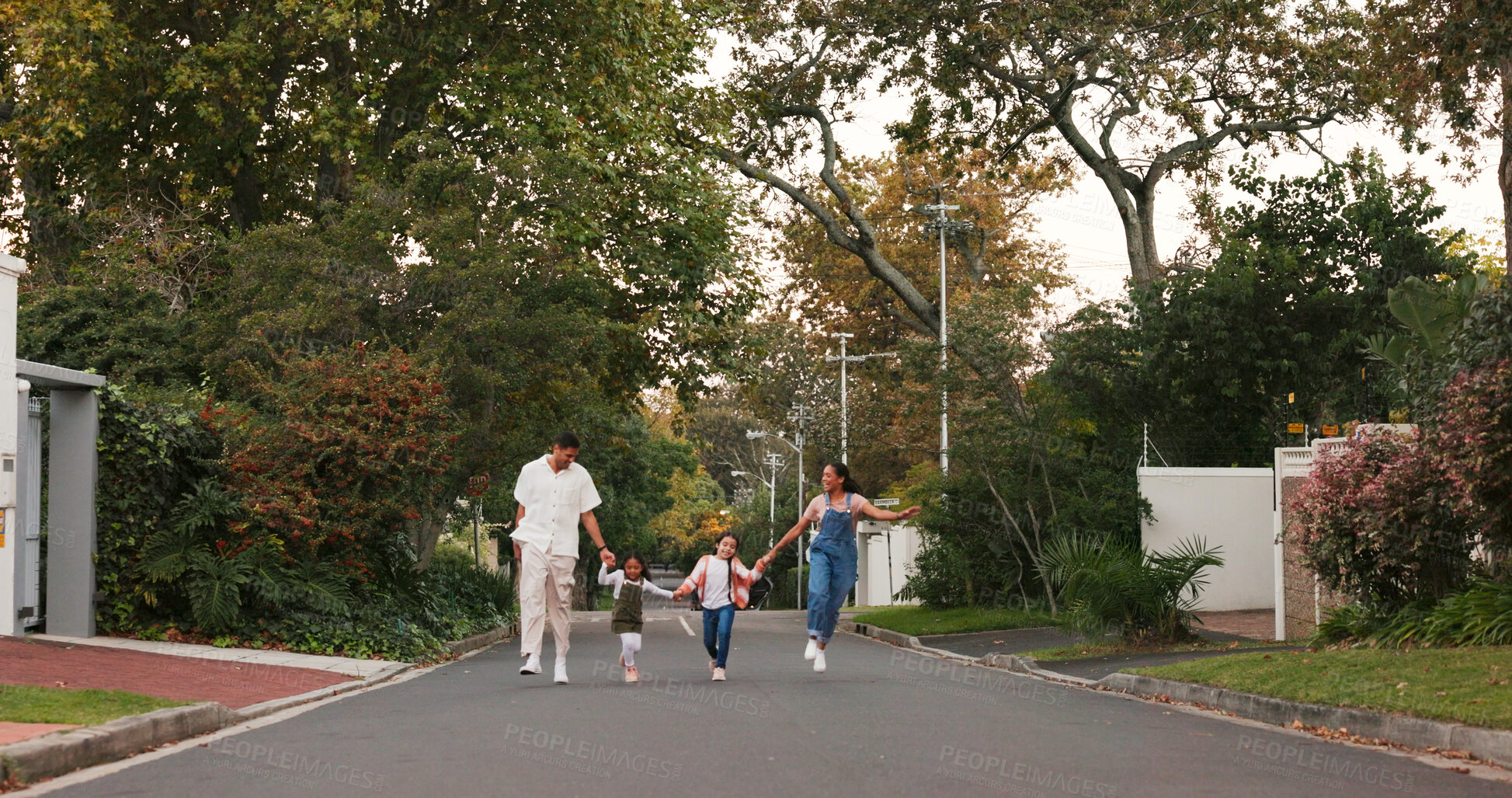 Buy stock photo Happy family, parents and kids with street skipping and playful with love, care and holding hands in neighborhood. Vacation and children with walk, excited and playing in road on summer school break