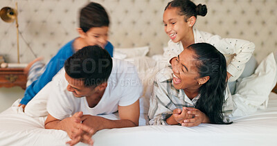 Happy family, mom and dad with children on bed, playing and bonding fun in home on weekend morning. Happiness, parents and kids joke in bedroom, playful quality time together and laughing with love.