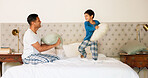 Playful, pillow fight and father and child in the bedroom for bonding, morning fun or playing together. Happy, family and young dad fighting with a kid and pillows on the bed of a house and laughing