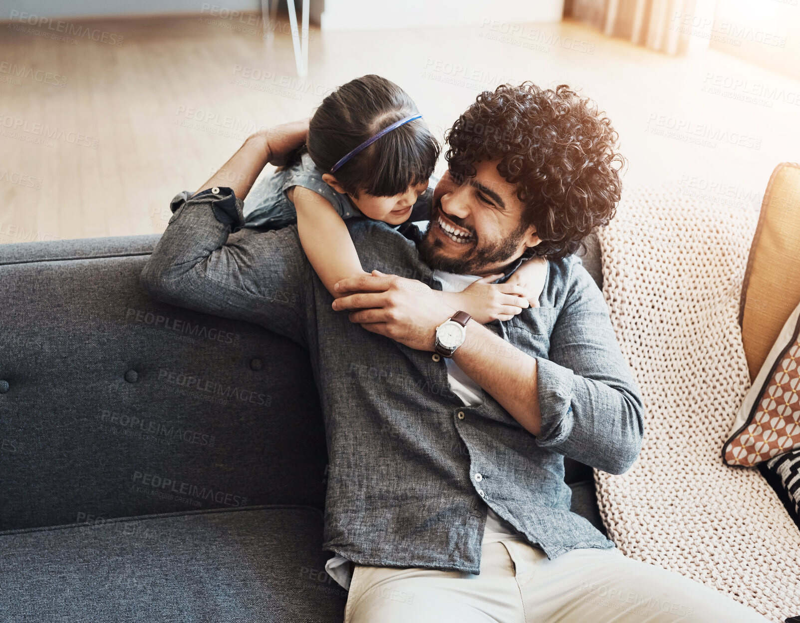 Buy stock photo Laughing, dad and girl with hug on sofa for love, appreciation and bonding together on weekend. Playful, family and man with embrace of daughter at home for gratitude, humor and safety in childhood