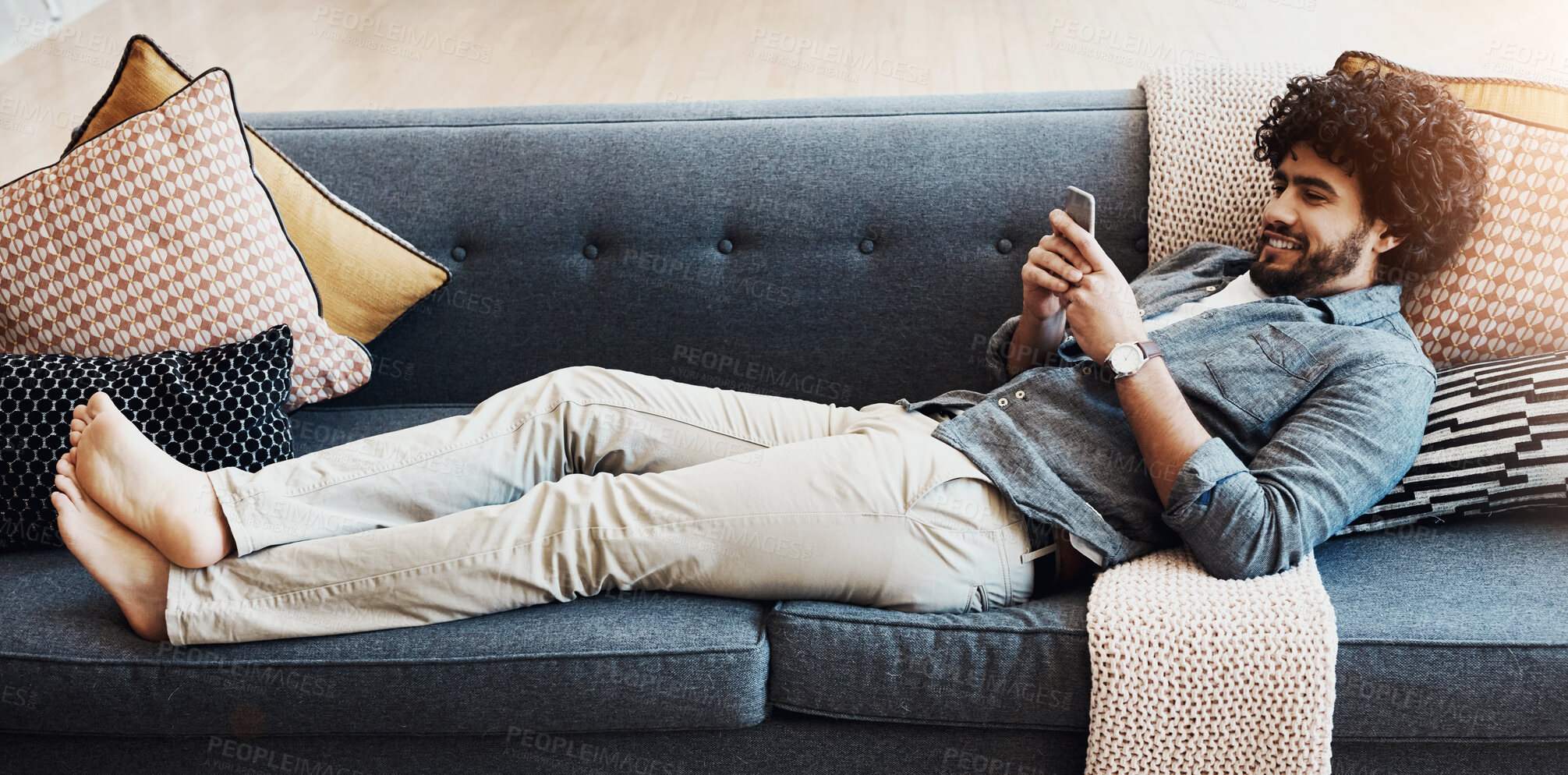 Buy stock photo Phone, rest and man on sofa in home happy for mortgage approval email for goal achievement. Banner, relax and male person laying on couch in living room with cellphone for communication online.