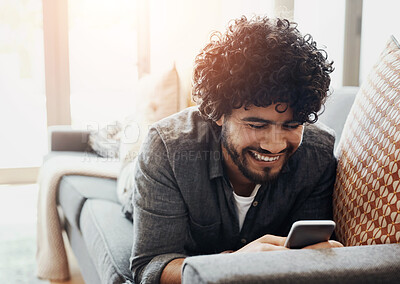 Buy stock photo Phone, relax and man on sofa in home happy for mortgage approval email for goal achievement. Smile, excited and male person laying on couch in living room with cellphone for communication online.