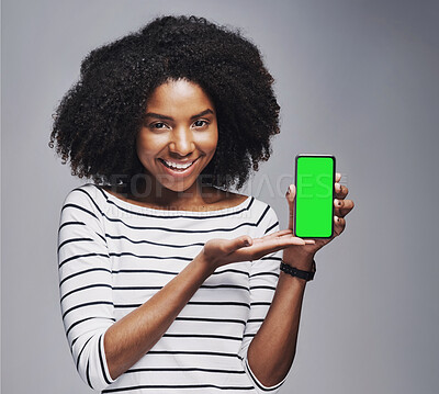 Buy stock photo Studio portrait of a young woman showing a smartphone with a green screen against a gray background