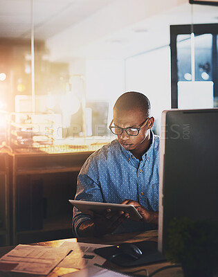 Buy stock photo Shot of a young businessman using a digital tablet during a late night in a modern office