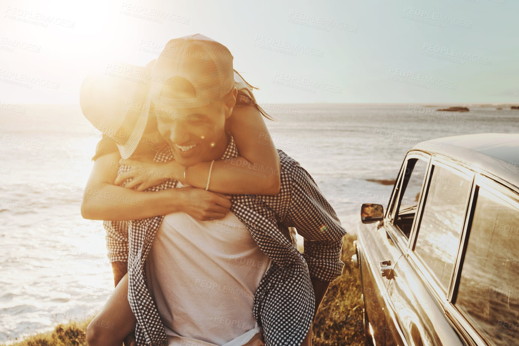 Buy stock photo Happy couple, sunset and piggy back at beach with car, smile or road trip on holiday adventure in summer. Man, woman and connection for love, playful or memory for bonding in sunshine by sea in Italy