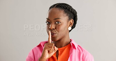 Buy stock photo Black woman, secret and smile with finger on lips for whisper or silence on a gray studio background. Portrait of happy African female person, face or looking secretive with gesture on mockup space