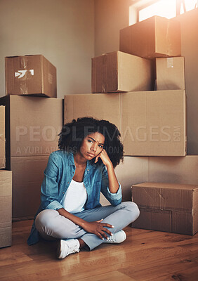 Buy stock photo Portrait of a unhappy looking young woman seated on the ground while being surrounded by cardboard boxes on moving day inside at home