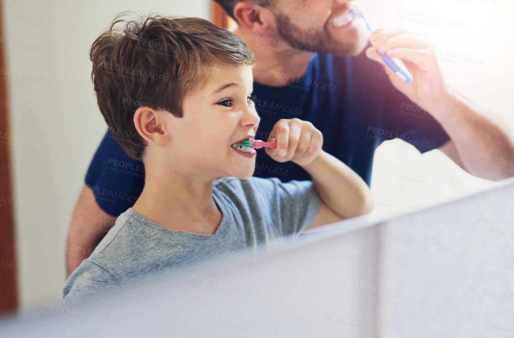 Buy stock photo Shot of a father and his little son brushing their teeth together at home