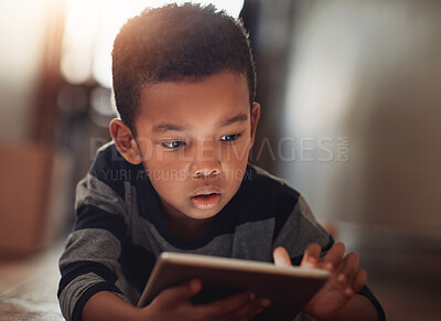 Buy stock photo Shot of a young boy using his digital tablet while lying on the floor at home