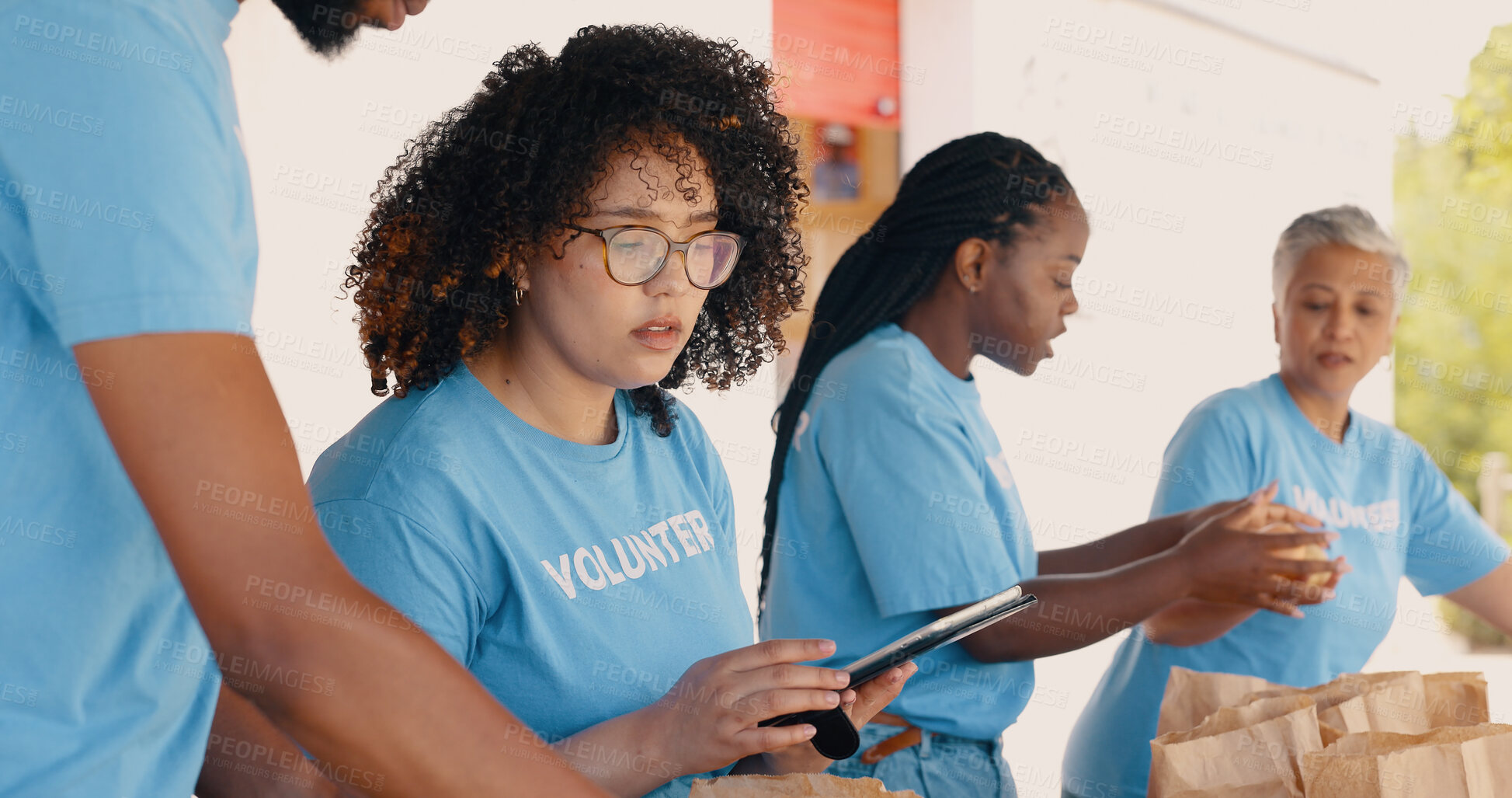 Buy stock photo Tablet, food donation and woman volunteering for non profit, charity and poverty support with checklist or management. Group of people packaging groceries, planning on digital technology and teamwork