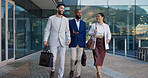 Business people, group and conversation in city on walk for commute to workplace with questions by buildings. Men, woman and employees with bag, outdoor and discussion for travel on metro sidewalk