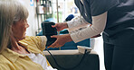 Woman, nurse and patient with blood pressure machine for heart rate or monitoring pulse at hospital. Hands of scrub with arm strap on senior person for healthcare, checkup or examination at clinic