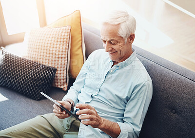 Buy stock photo Cropped shot of a senior man relaxing and using a tablet on the sofa at home