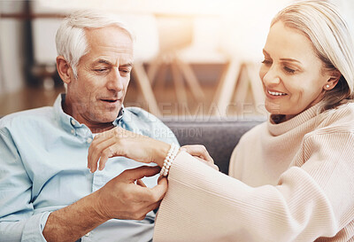 Buy stock photo Mature couple, gift and home with jewelry for anniversary, love and romantic gesture in living room. Happy woman, sofa and man with bracelet for milestone, birthday present and support in marriage