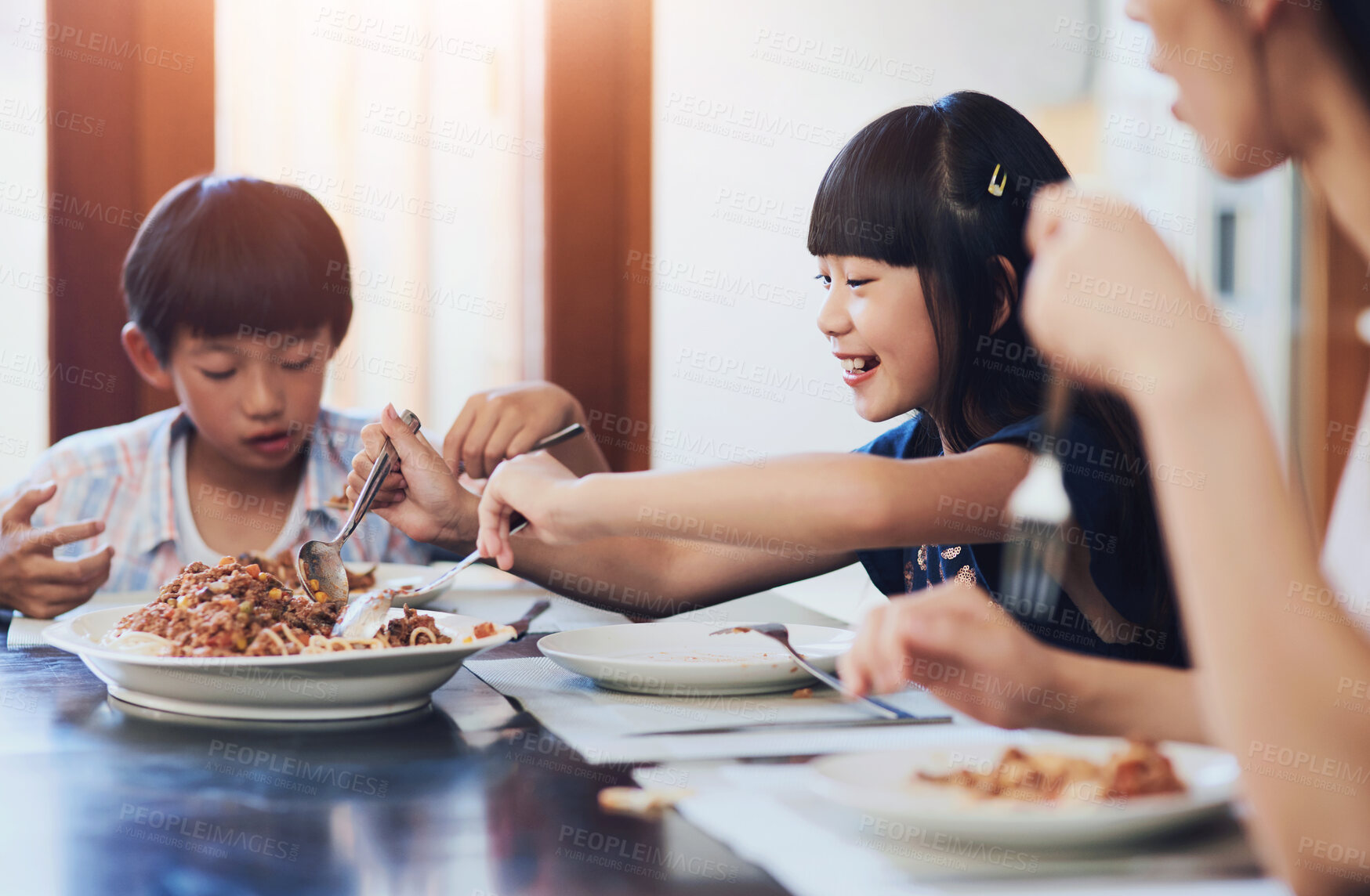 Buy stock photo Shot of two little children enjoying a meal with their mother at home