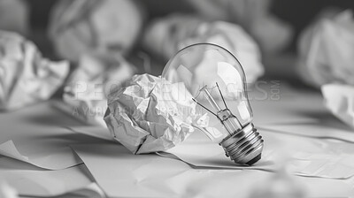 Light bulb, ideas and crumpled paper for creative solution, writing and brainstorming on desk. Research, planning and inspiration with power, solution or problem solving for startup project or career