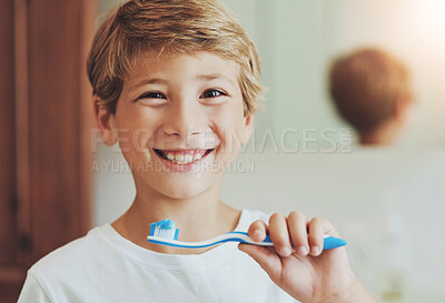 Buy stock photo Portrait of a cheerful young boy looking at his reflection in a mirror while brushing his teeth in the bathroom at home during the day