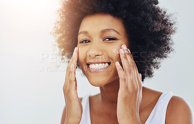 Buy stock photo Cropped shot of an attractive young woman applying moisturizer on her face in the bathroom at home