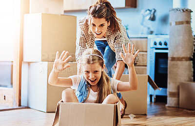 Buy stock photo Shot of a cheerful young woman pushing her daughter around in a box imagining its a car inside at home during the day
