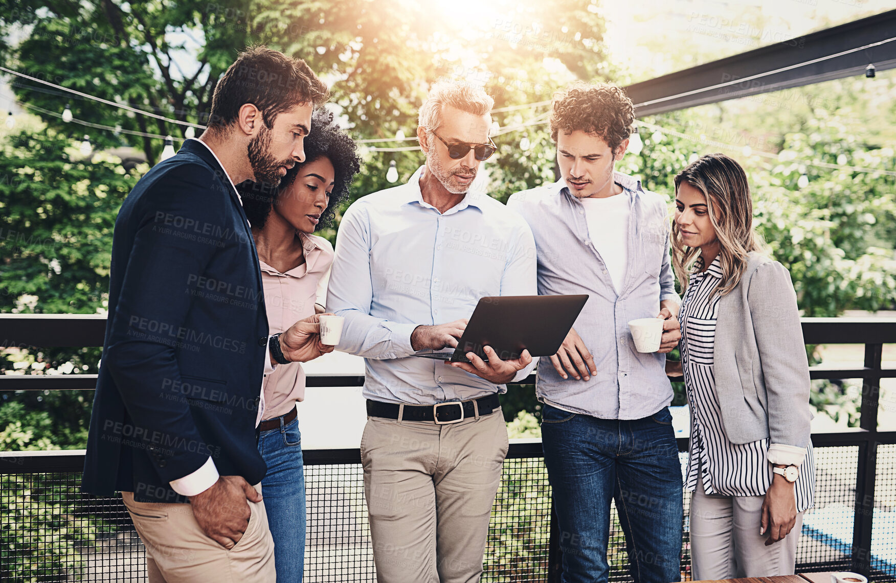 Buy stock photo Shot of a group of businesspeople working together on a laptop outside