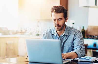 Buy stock photo Shot of a handsome young man working on a laptop at home