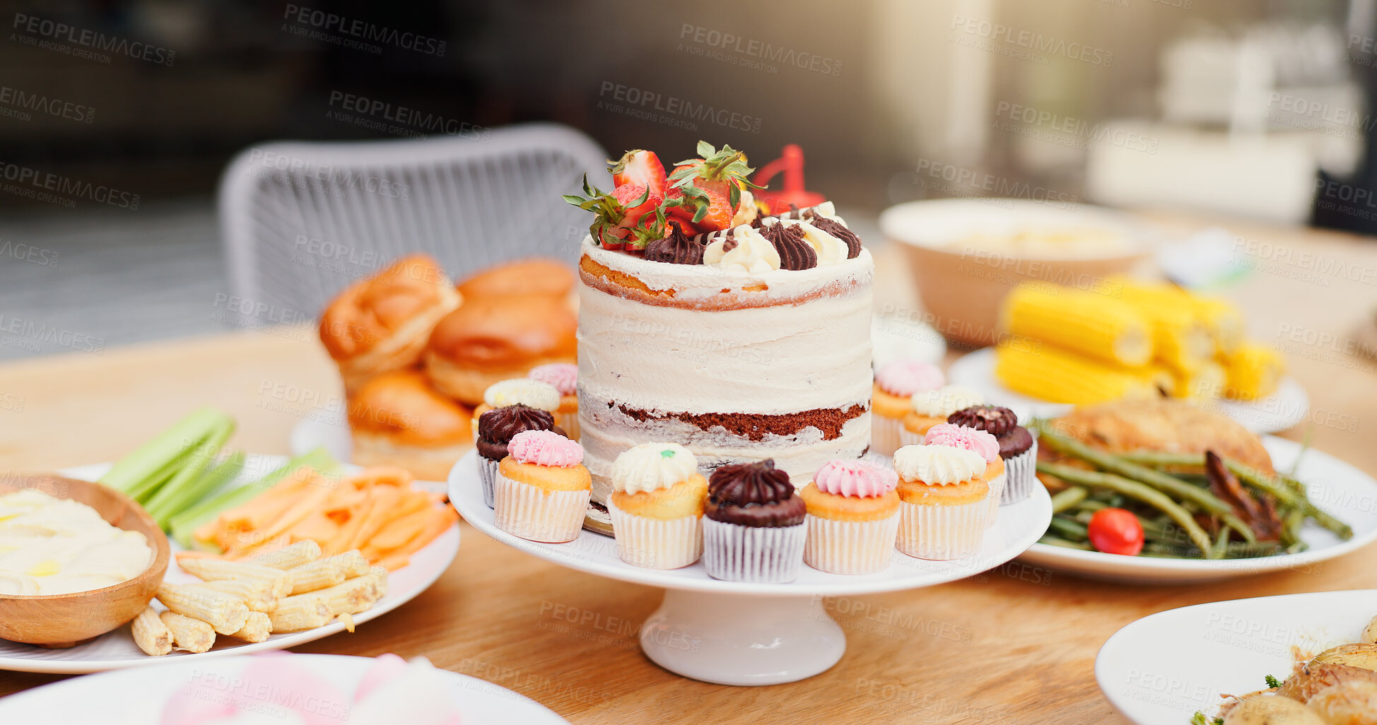 Buy stock photo Birthday cake, table and food for event, celebration and party on patio with lunch meal. Dessert, home and outdoor with feast, vegetable and sweet baking with cupcake and sugar snack on a plate