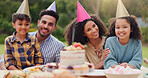 Parents, children and happy with birthday cake in garden with care, love and bonding with food at family home. Father, mother and kids with hat for party, event and embrace at table with celebration