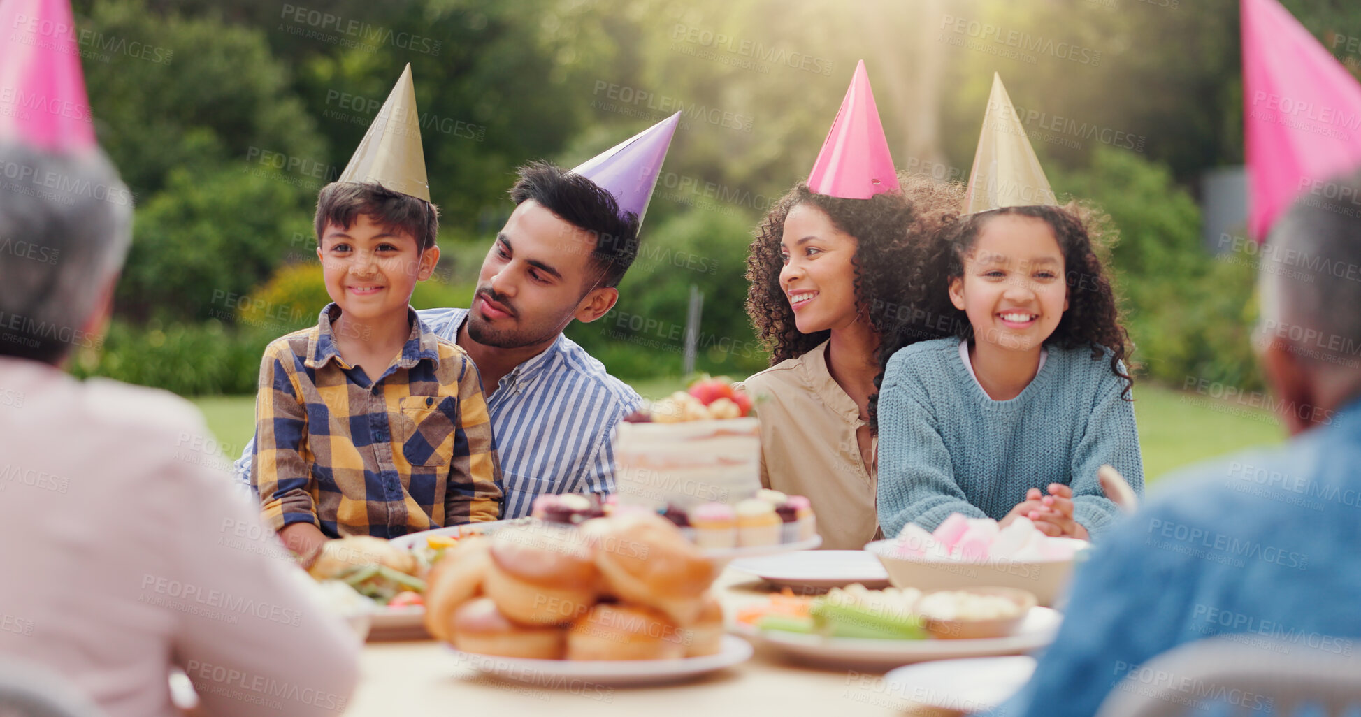 Buy stock photo Parents, children and happy with birthday cake in garden with care, love and bonding with food at family home. Father, mother and kids with hat for party, event and embrace at table with celebration