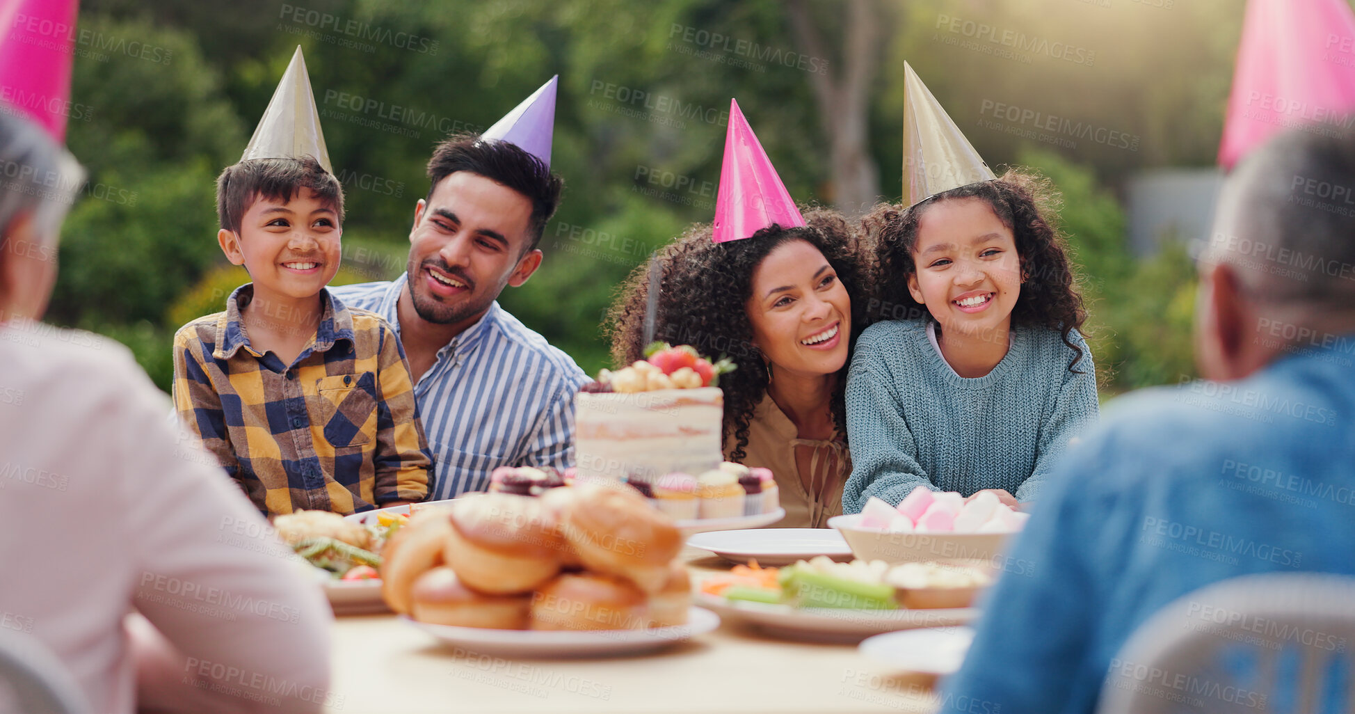 Buy stock photo Parents, children and happy with birthday cake in garden with care, love and bonding with food at family home. Father, mother and kids with hat for party, event and embrace at table with celebration