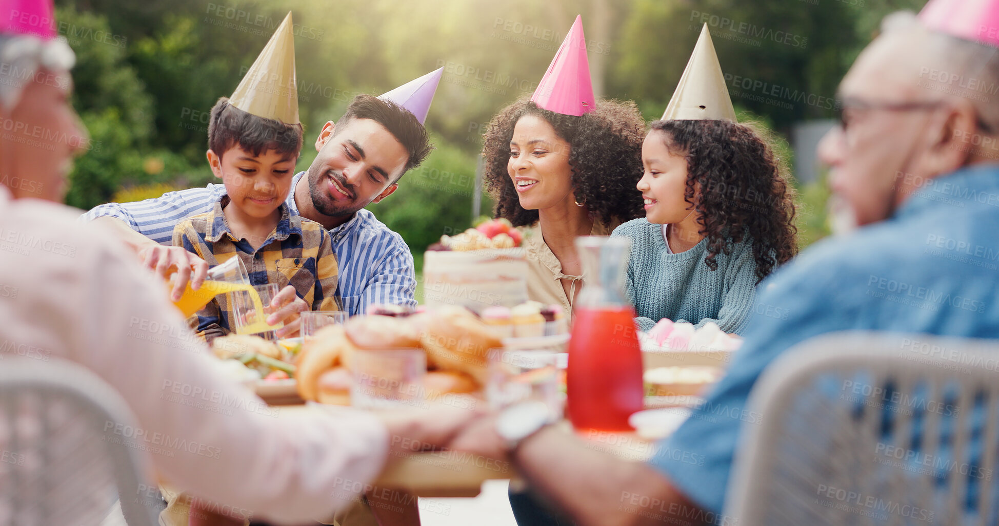 Buy stock photo Children, parents and happy with hat at birthday party for celebration, laughing or memories in garden of home. Family, people or kids with eating for bonding, gathering or event in backyard of house