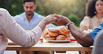 Holding hands, prayer and food with thanks, religion and backyard with family and lunch. Faith, worship and praying at a table for blessing together on a patio outdoor from a home at a gathering