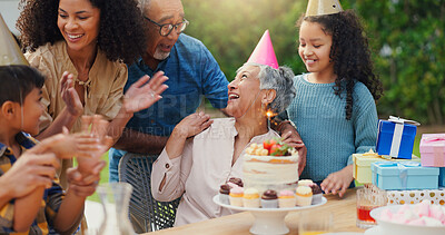 Senior woman, birthday cake and family in garden with applause, celebration and happy together for party. Man, women and children in grandparents backyard with present, dessert and love in summer