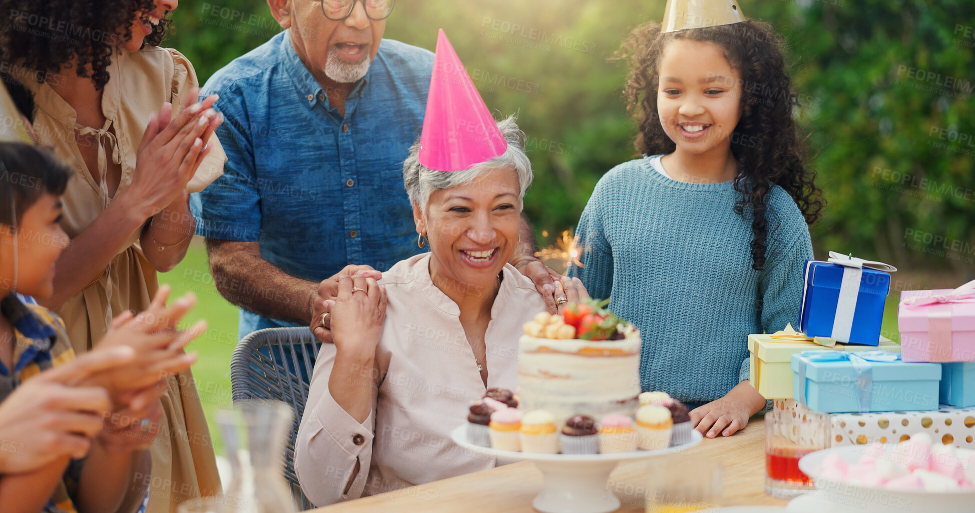 Buy stock photo Senior woman, birthday cake and family in garden with applause, celebration and happy together for party. Man, women and children in grandparents backyard with present, dessert and love in home