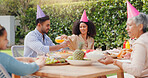 Family, eating and happy with hat at birthday party for celebration, surprise or conversation in garden of home. Couple, parents and kids with drinks for gathering and event in backyard of house