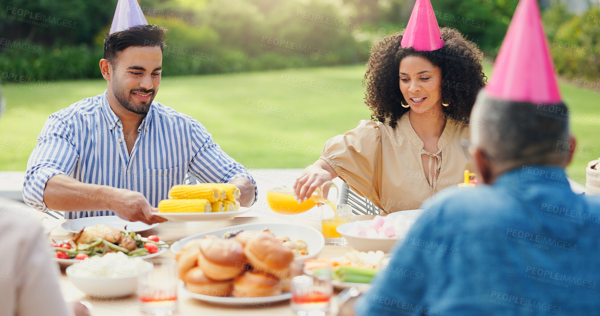 Buy stock photo Family, men and women at birthday party in garden with hat, happy and giving food at brunch in summer. People, relax and holiday with celebration, event and together for eating corn in home backyard