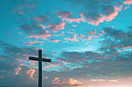 Outdoor, sunset and cross for religion, clouds and spiritual with faith, holy and symbol for forgiveness. Compassion, worship and countryside with Christian icon, resurrection and believe in Christ