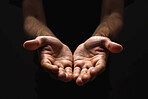 Person, hands and praying with faith for religion, god or submission on a dark studio background. Closeup of prayer with light on palms together for hope, charity or care in support, peace or offer