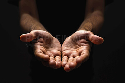 Person, hands and praying with faith for religion, god or submission on a dark studio background. Closeup of prayer with light on palms together for hope, charity or care in support, peace or offer