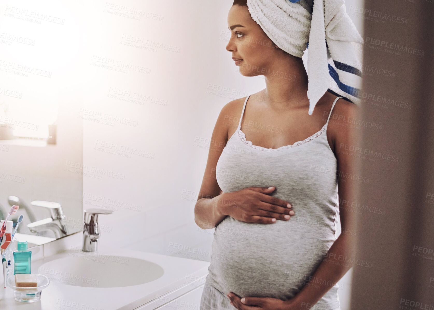 Buy stock photo Pregnancy, motherhood and african woman in home for maternity leave, holding and touching baby bump. Bathroom, pregnant girl and belly growth, expectation and prenatal with smile in morning by house