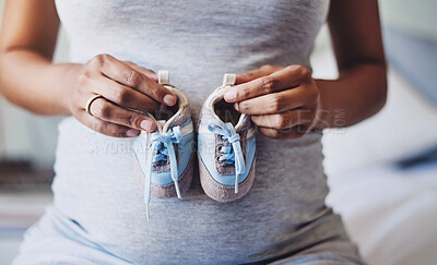 Buy stock photo Cropped shot of a pregnant woman holding a pair of blue baby shoes in front of her belly
