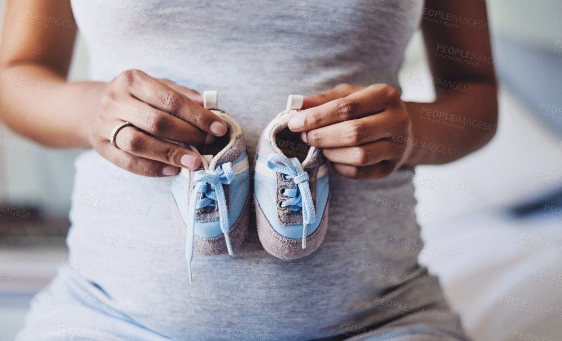 Buy stock photo Hands, baby shoes and pregnant woman with love, stomach and anticipation in apartment. Closeup, person and girl with belly, sneakers or pregnancy with wellness, hope for future or motherhood in house