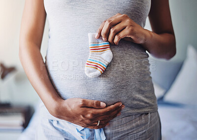 Buy stock photo Cropped shot of a pregnant woman holding a baby’s sock in front of her belly