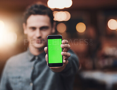 Buy stock photo Shot of a confident young man holding up a cellphone to the camera while standing inside of a beer brewery during the day
