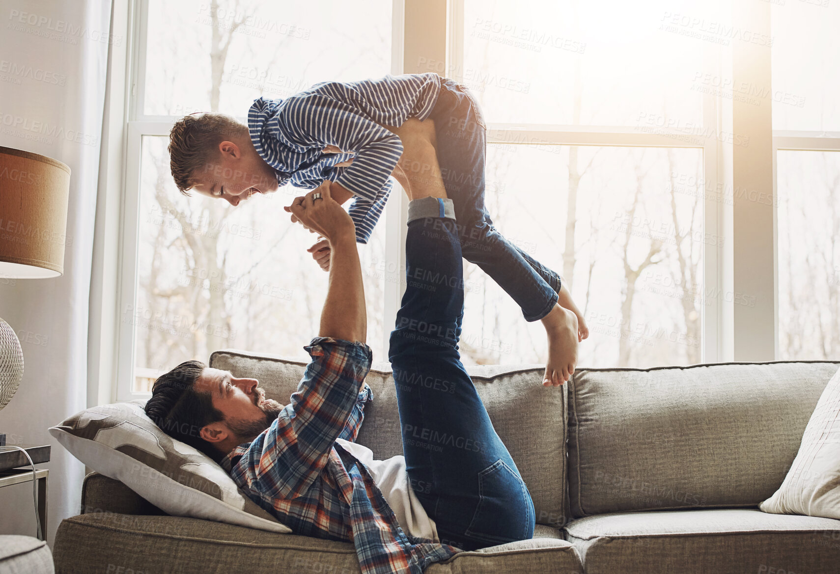 Buy stock photo Dad, son and support on sofa with lift for bonding, together for relationship or game. Father, boy child and strong legs for air play or development in house, relax with learning in family home