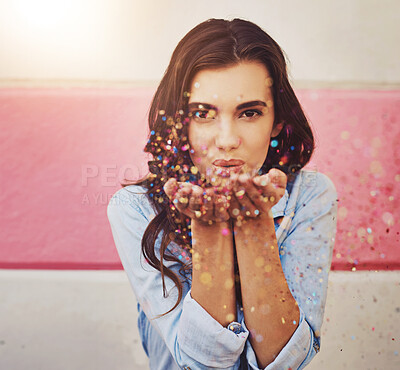 Buy stock photo Portrait of a beautiful young woman blowing confetti outside