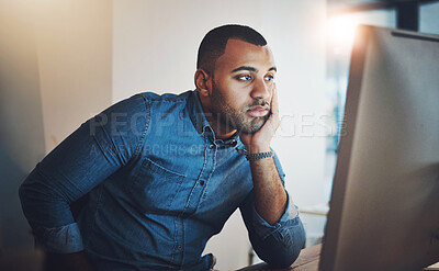 Buy stock photo Shot of a young businessman looking bored while working during a late night in a modern office