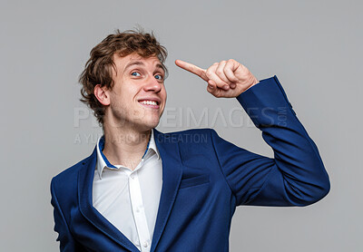 Man, professional and pointing to head in studio, thinking and smile on gray background for idea. Male person, gesture and pride for solution or problem solving, employee and confident for plan