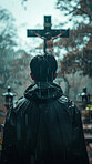 Man, cemetery and outdoor with walk in rain, back and cross for mourning, faith or faith with religion. Person, graveyard and reflection by crucifix in storm with depression, loss and death in winter